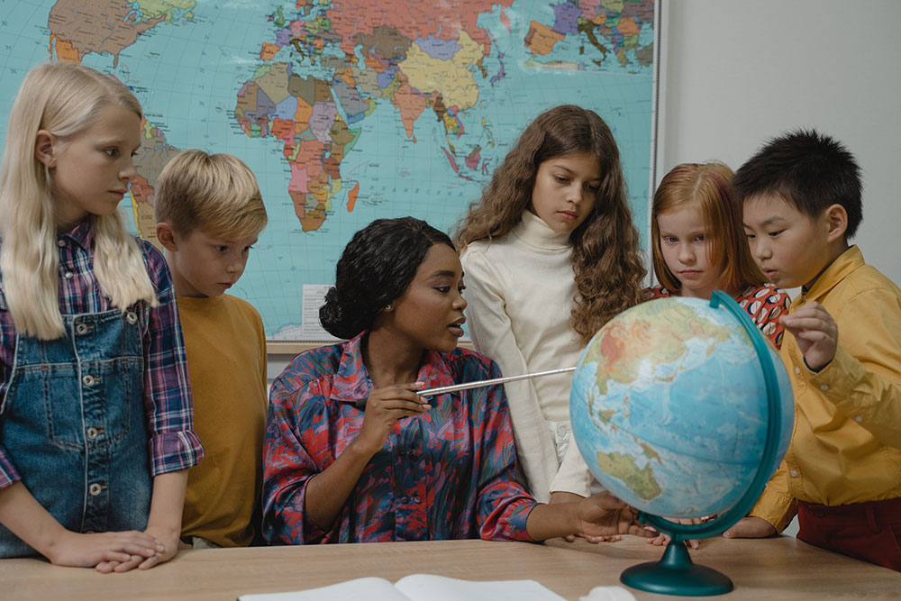 a teacher pointing to a globe, applying a calming technique for students with autism