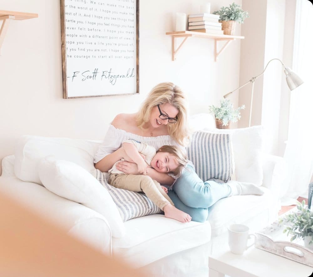 woman sitting on a couch with her child smiling with support from therapy