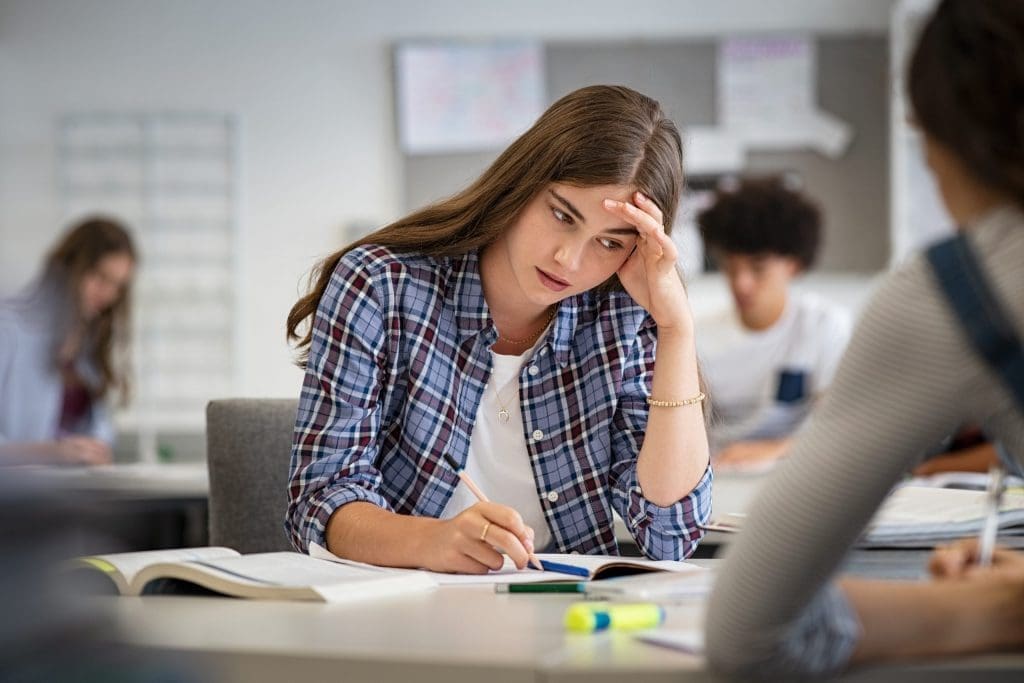 Students experiencing test anxiety during an exam in a classroom, feeling stressed while studying for tests.